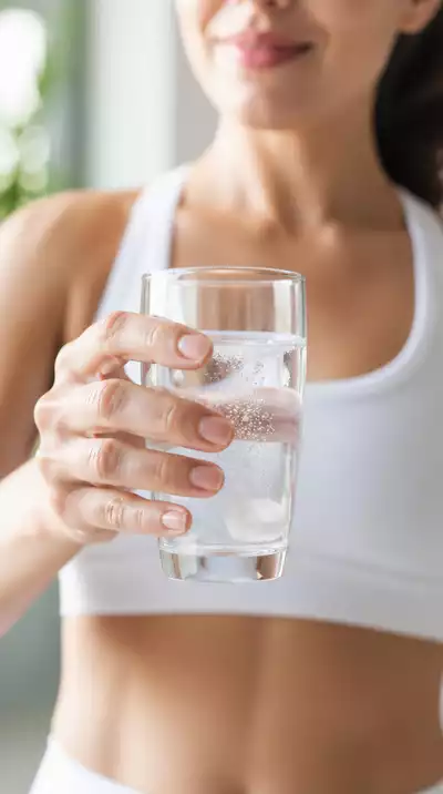 Person drinking water with electrolyte supplement during a fast